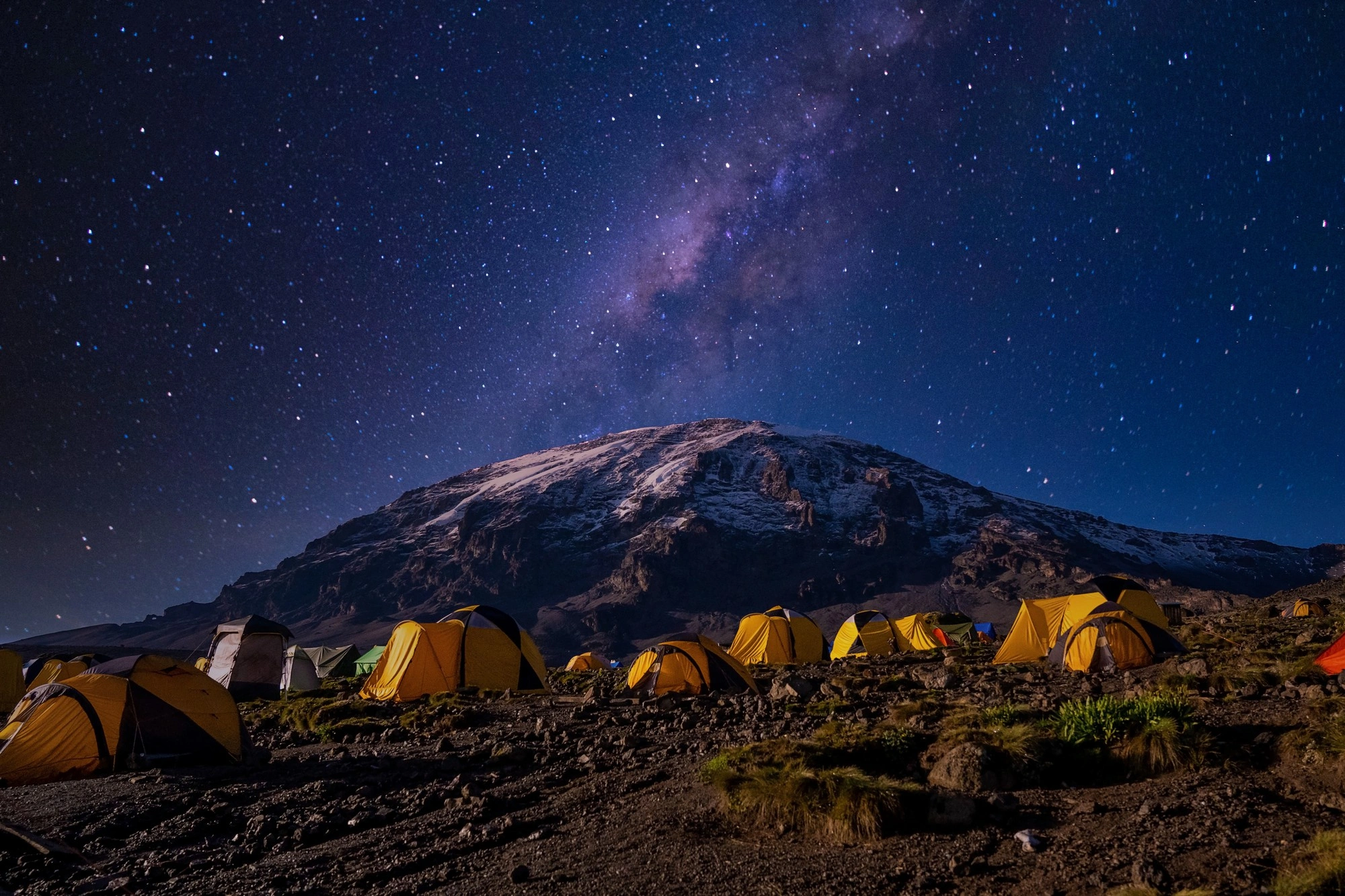 Trekkers climbing Mount Kilimanjaro beneath a star-filled sky